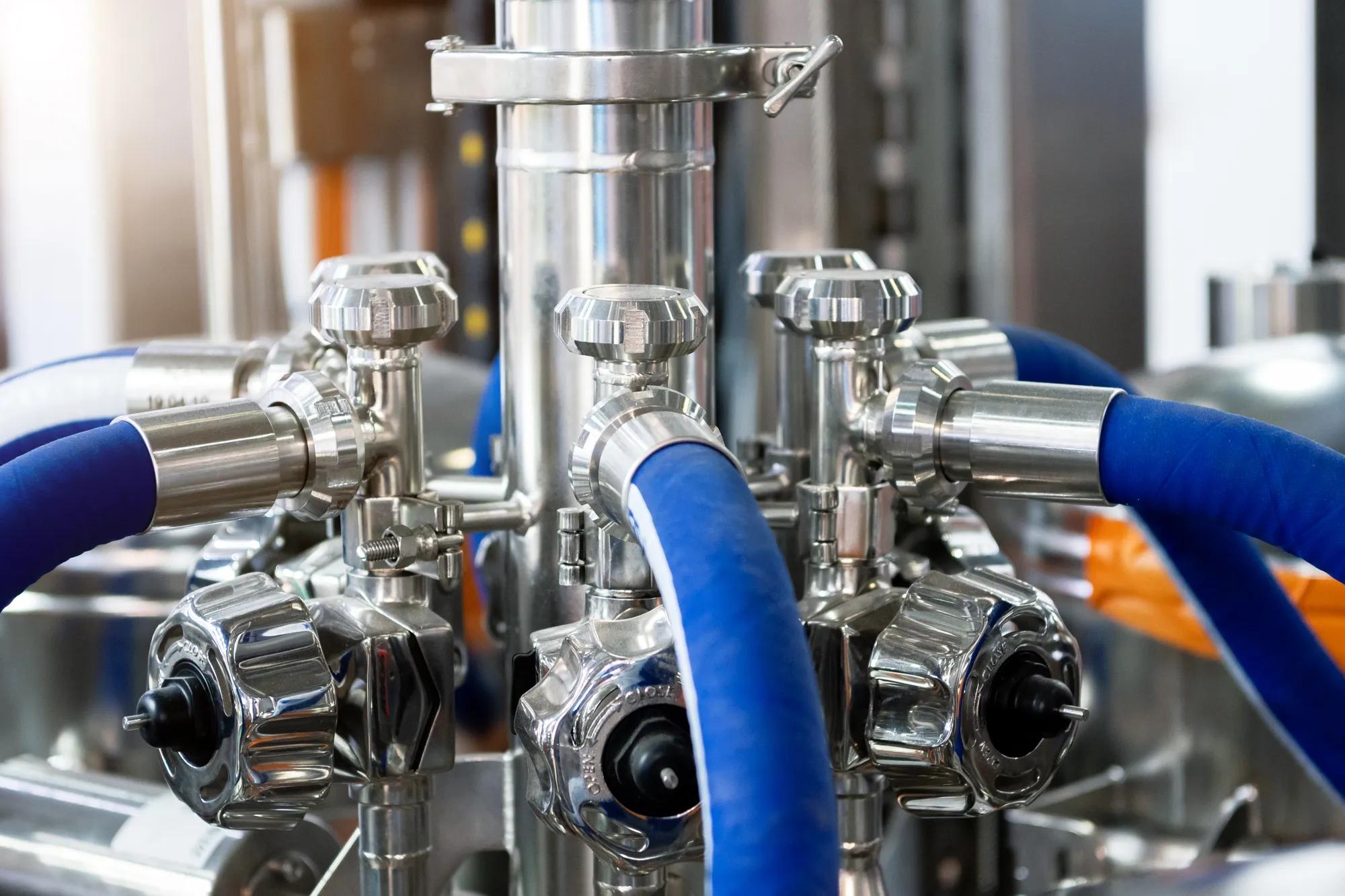 Bright shiny stainless steel piping. Distribution system of ball valves and metal piping, sensors and rubber hoses. Equipment for the food industry.