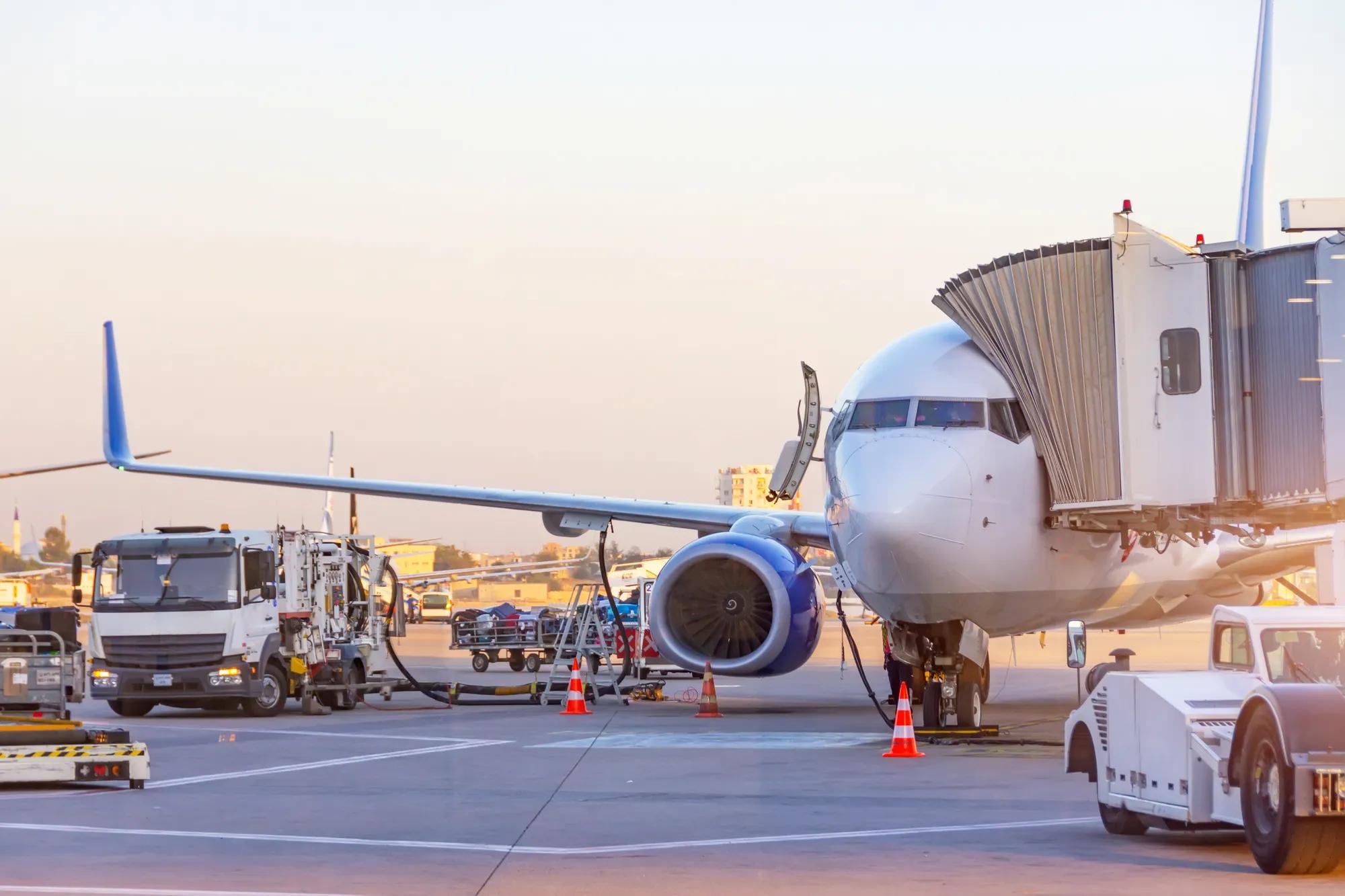 Passenger plane parked at the airport. Refueling operation in action during sunset. Fuel kerosene tanker vehicle. Handling and preparing for departure. Aircraft ground maintenance, pre flight service