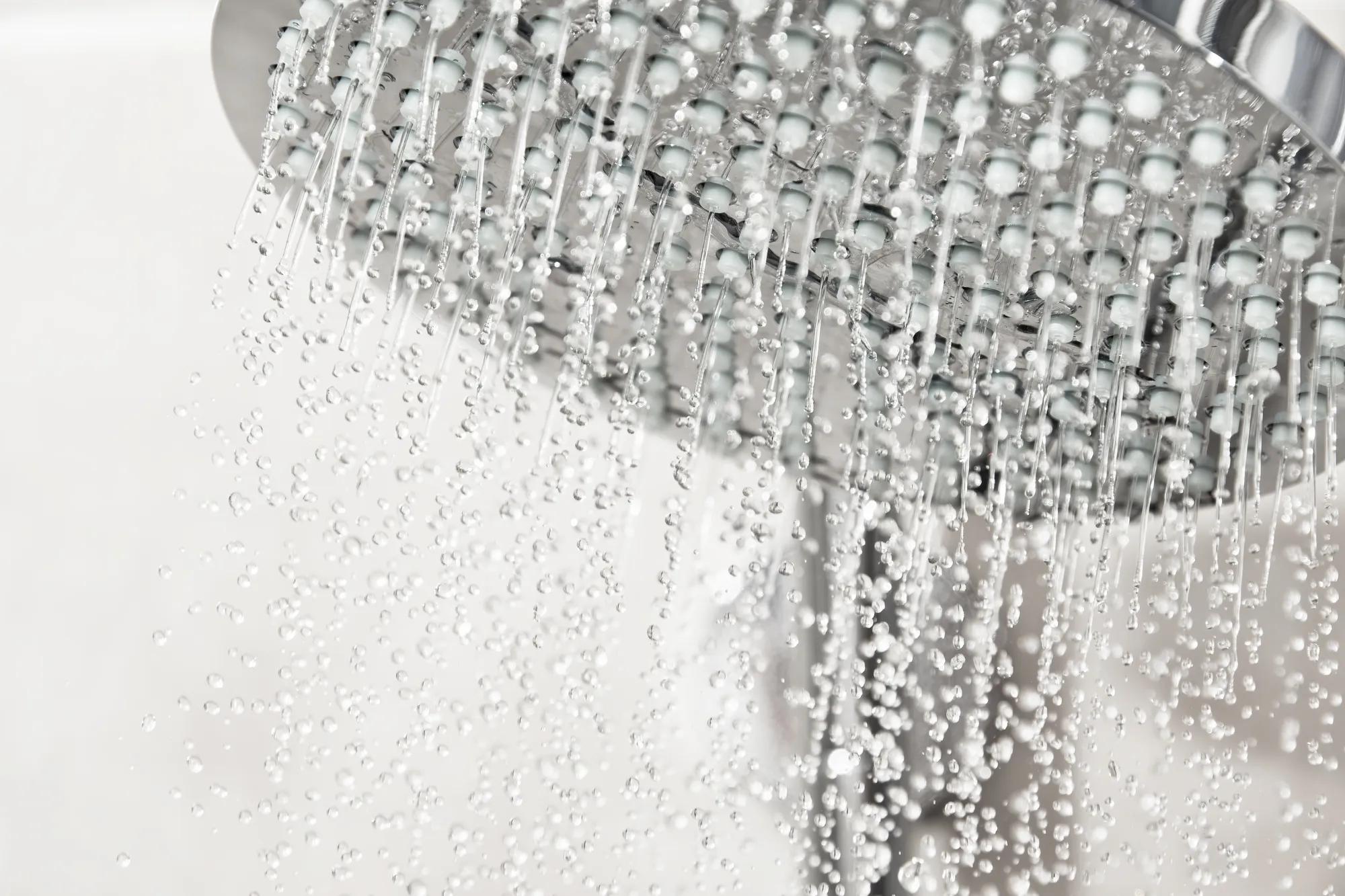 Clean water drops pours from the shower head in the light bathroom. Detailed water and shower equipment. Adobe Stock 678193758