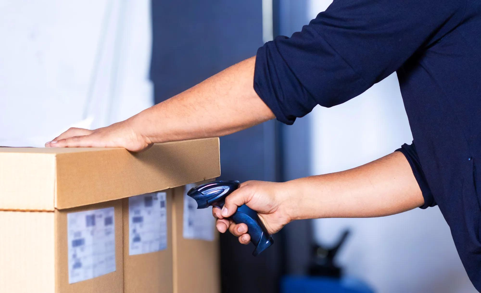 An operator scanning a cardboard box before shipment to verify logistics information.