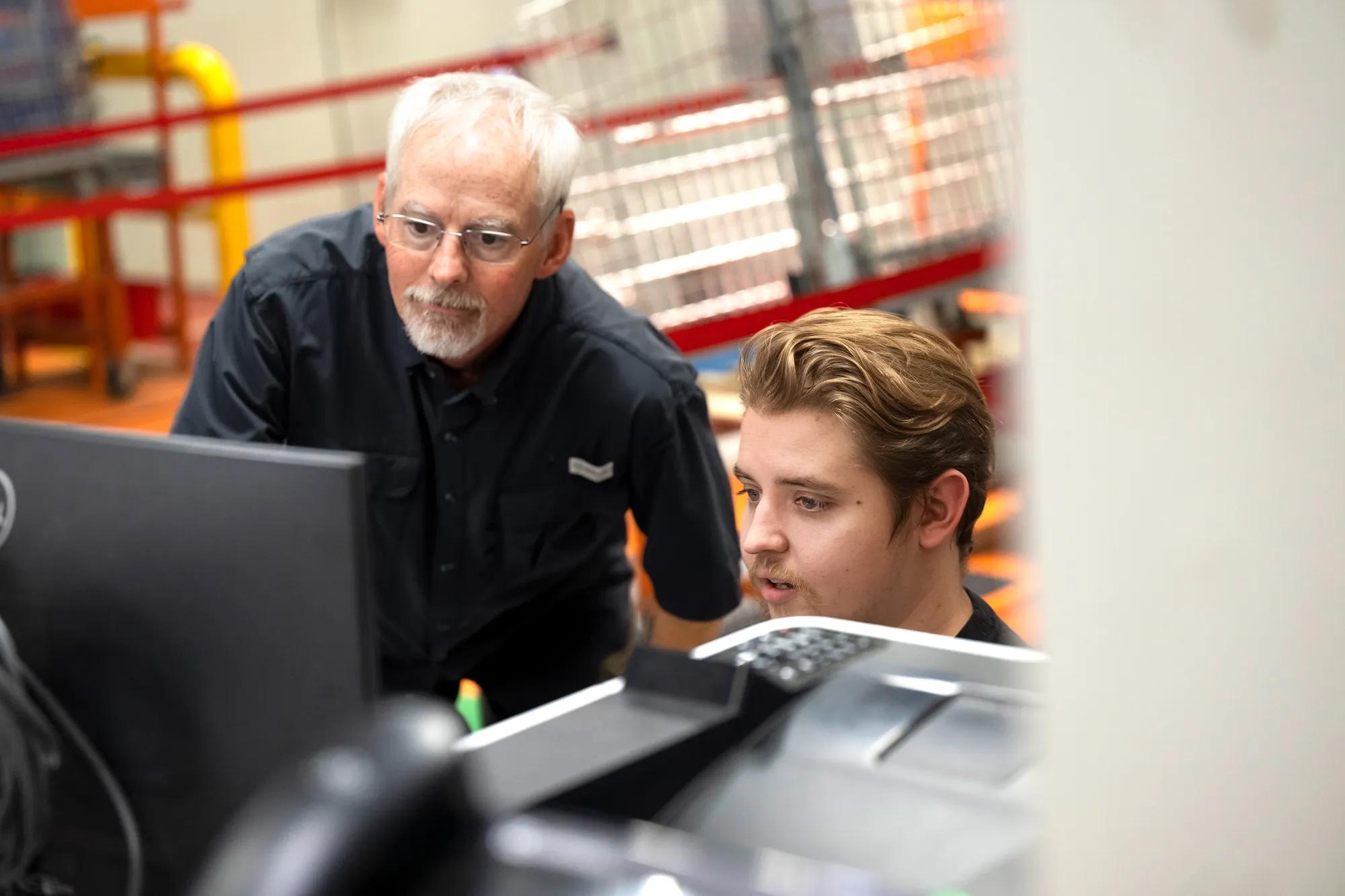 Two employees discuss work at a computer on the shop floor of the Salisbury facility.