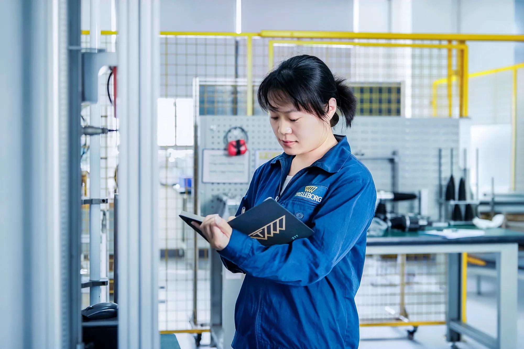 An employee recording data in front of an operating bench test machine.