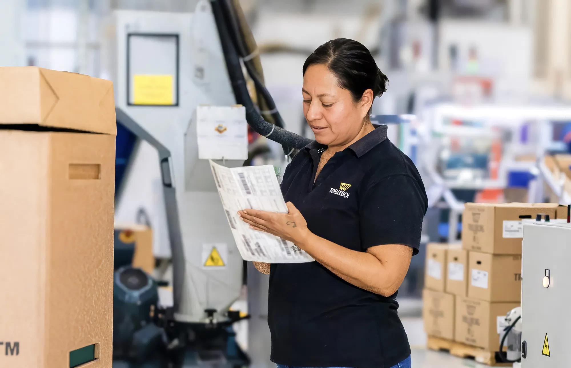An operator preparing a logistics label to be attached to a cardboard box for shipment tracking.