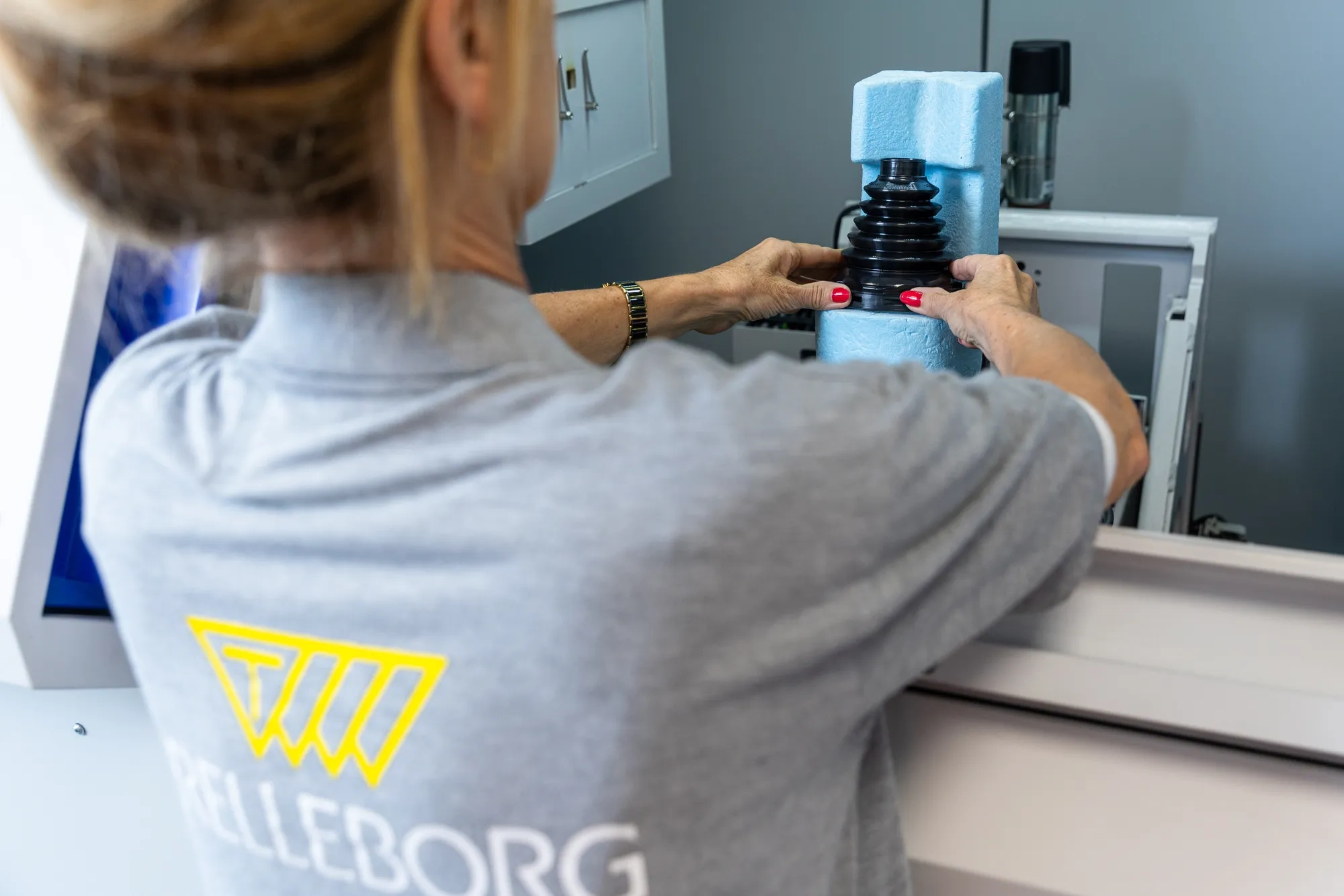 Operator placing a CVJ boot inside an X-ray inspection machine to analyze wall thickness, material distribution, and geometric curves for quality control.