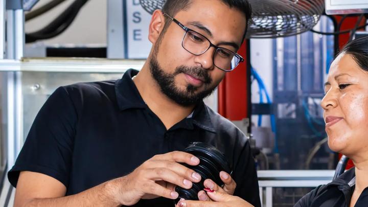 Two Trelleborg operators jointly inspecting a product at a quality control workstation.
