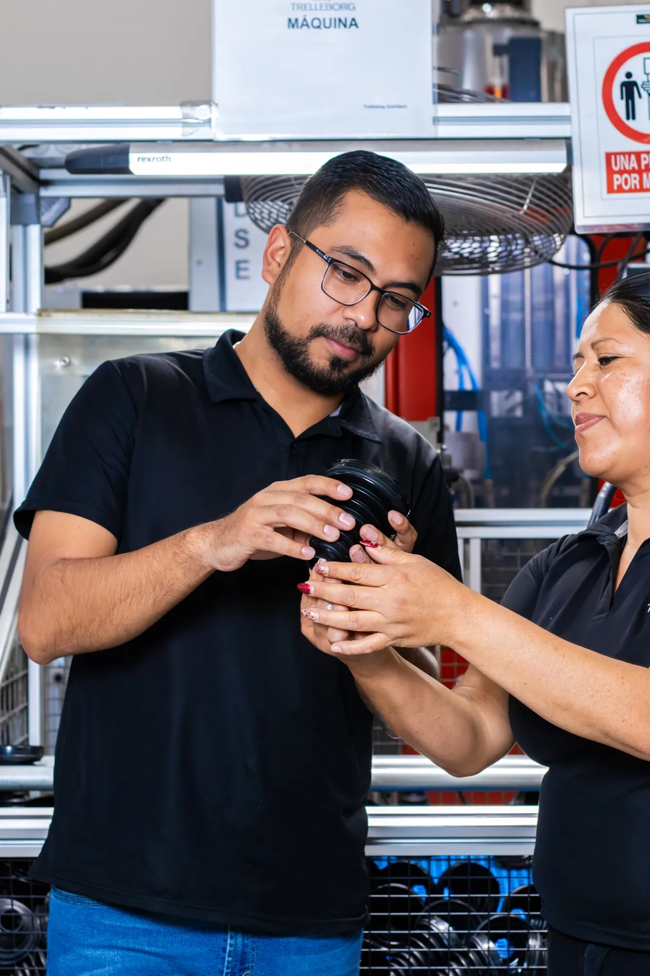 Two Trelleborg operators jointly inspecting a product at a quality control workstation.