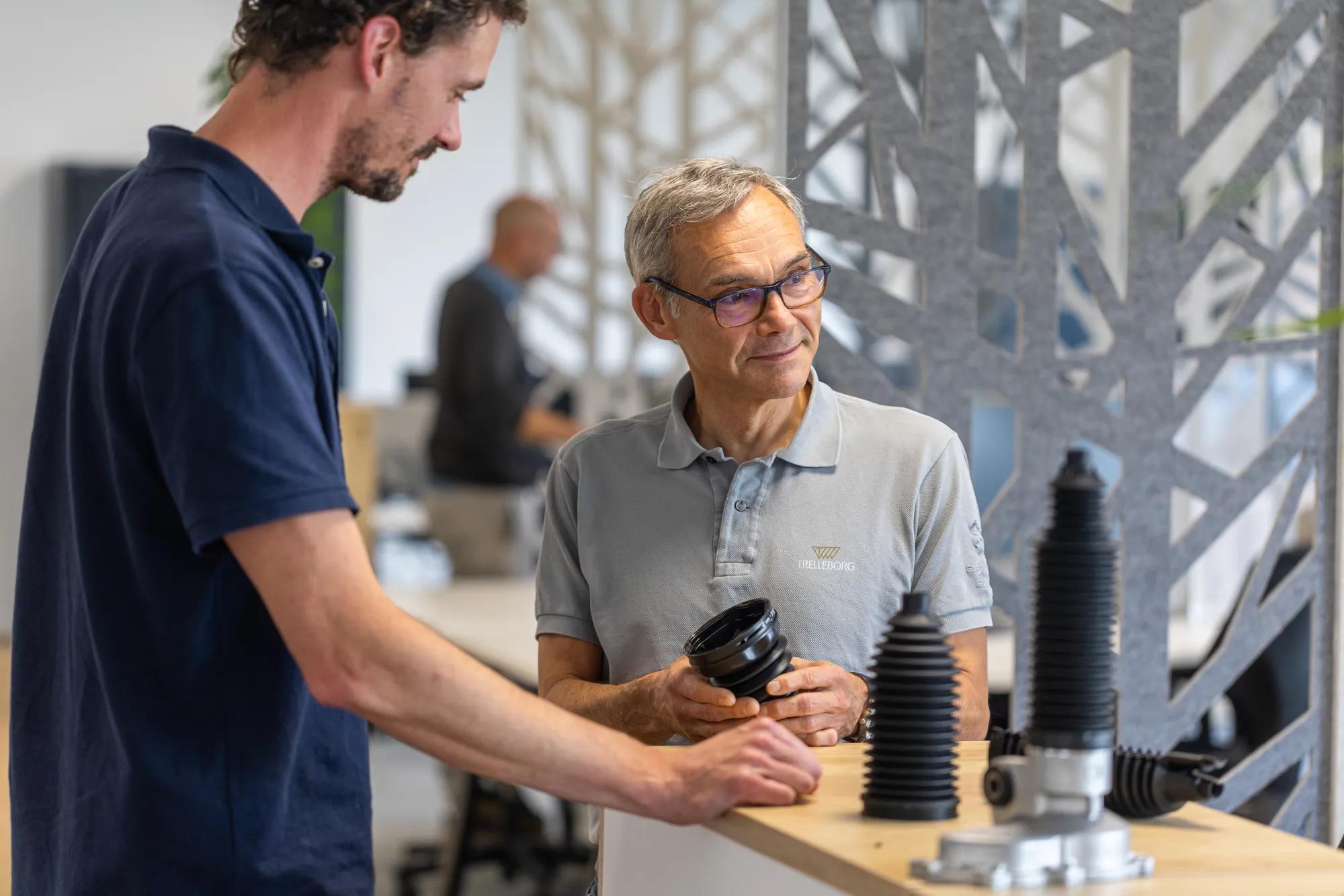 Two Trelleborg engineers in an office discussing the design and performance of a CVJ trilobe boot, sharing technical knowledge and expertise.
