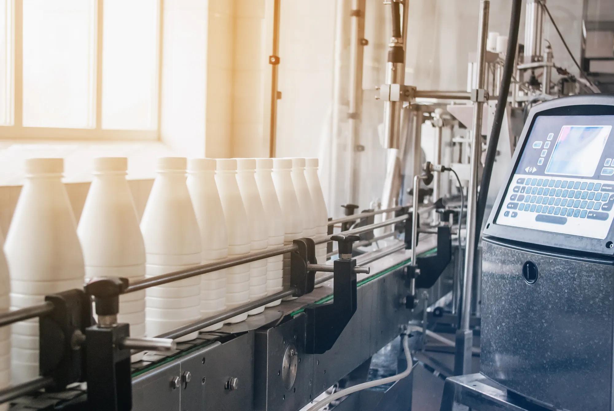 White plastic bottles with dairy product on production line. Bottled on conveyor.