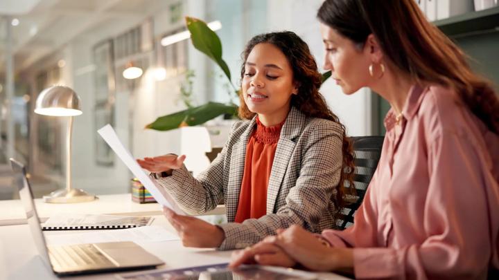 Planning, reading and financial advisor with client for document, investment discussion and tips. Business office, women team and talking with paperwork for policy review, laptop or corporate meeting.