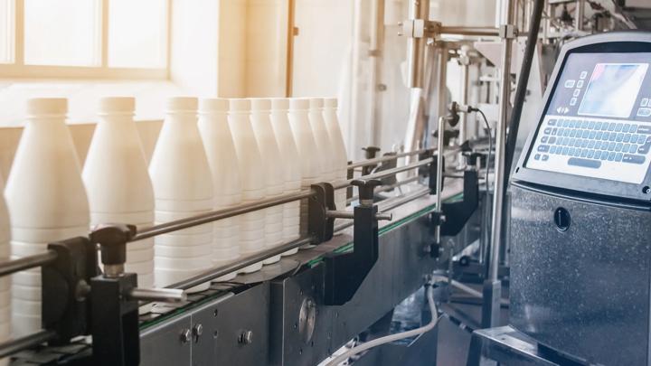 White plastic bottles with dairy product on production line. Bottled on conveyor.