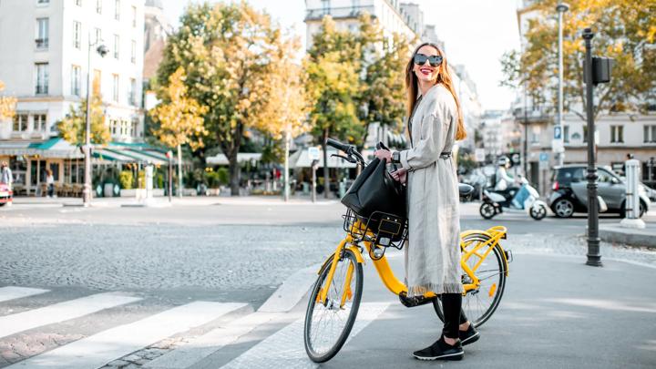 Portrait of a young stylish woman with yellow bicycle on the street in Paris