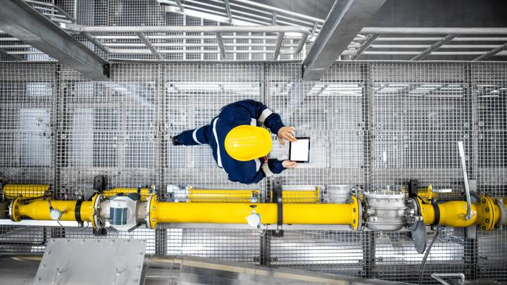 Top view of refinery worker walking by gas pipes, checking gasoline supply and installations in production plant.