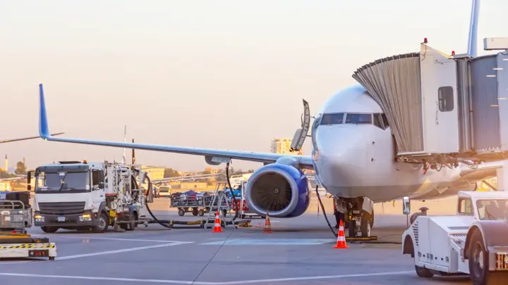 Passenger plane parked at the airport. Refueling operation in action during sunset. Fuel kerosene tanker vehicle. Handling and preparing for departure. Aircraft ground maintenance, pre flight service