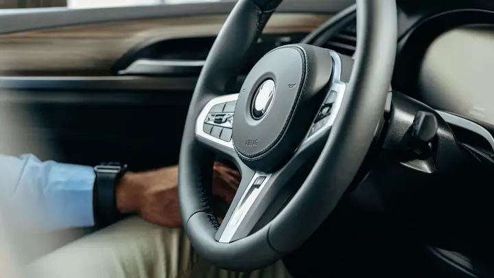 Male hands holding steering wheel of a car close up