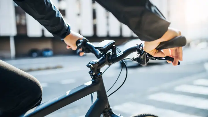 A midsection of businessman commuter with electric bicycle traveling to work in city. A close-up.