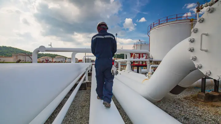 Male worker inspection at steel long pipes and pipe elbow in station oil factory during refinery valve of visual check record pipeline oil and gas industry.