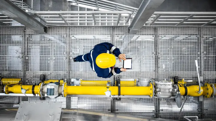 Top view of refinery worker walking by gas pipes, checking gasoline supply and installations in production plant.