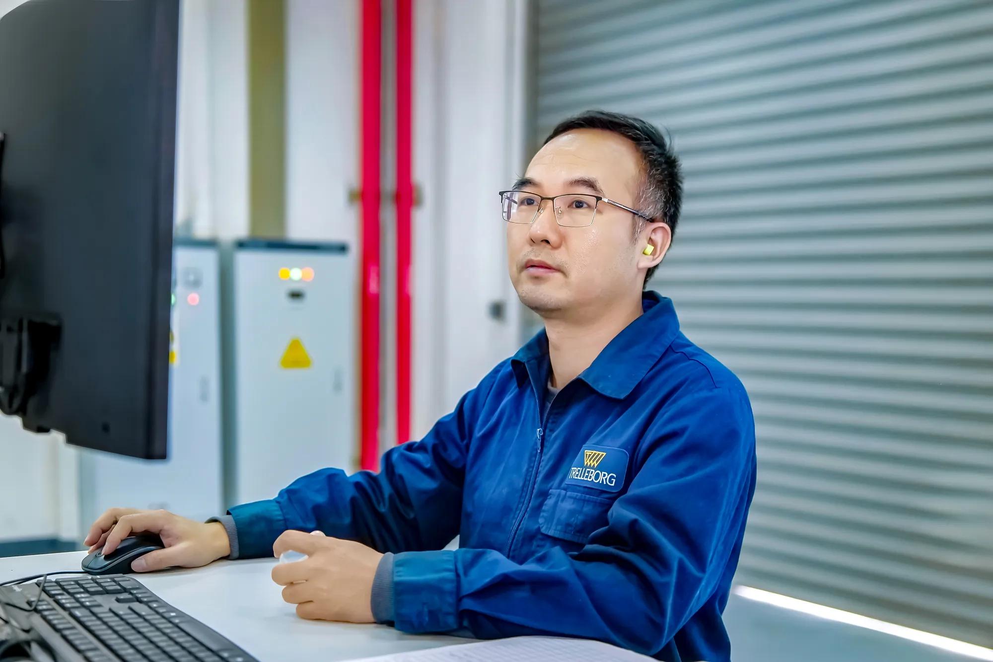 An employee at Trelleborg Wuxi Boots' facility reviews data on his computer before running bench tests.