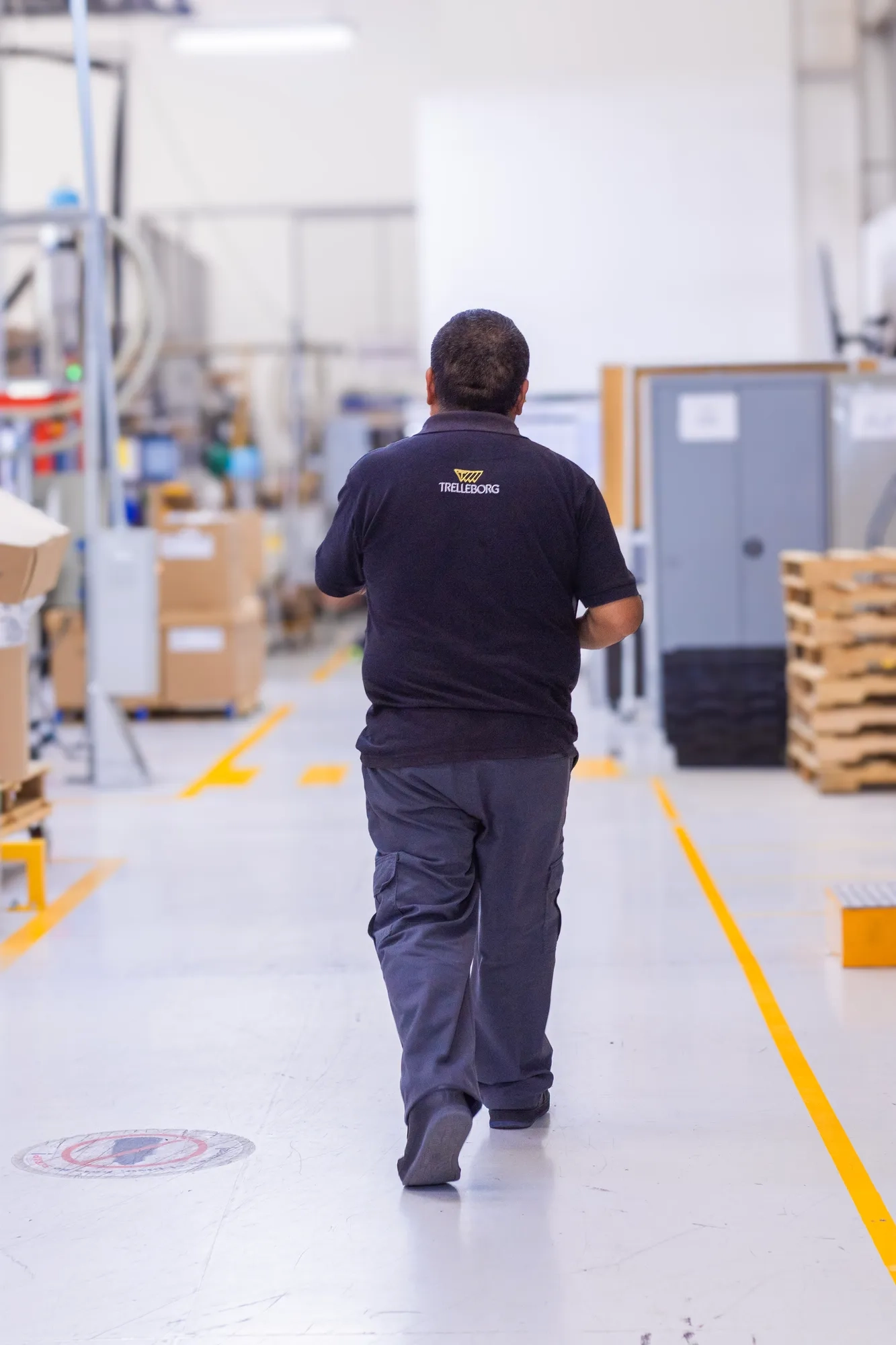 An operator wearing Trelleborg workwear walking across the production floor.