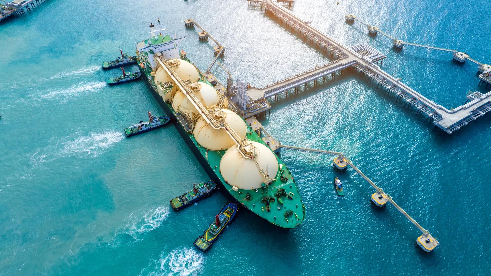 LNG (Liquefied natural gas) tanker anchored in Gas terminal gas tanks for storage. Oil Crude Gas Tanker Ship. LPG at Tanker Bay Petroleum Chemical or Methane freighter export import transportation	
