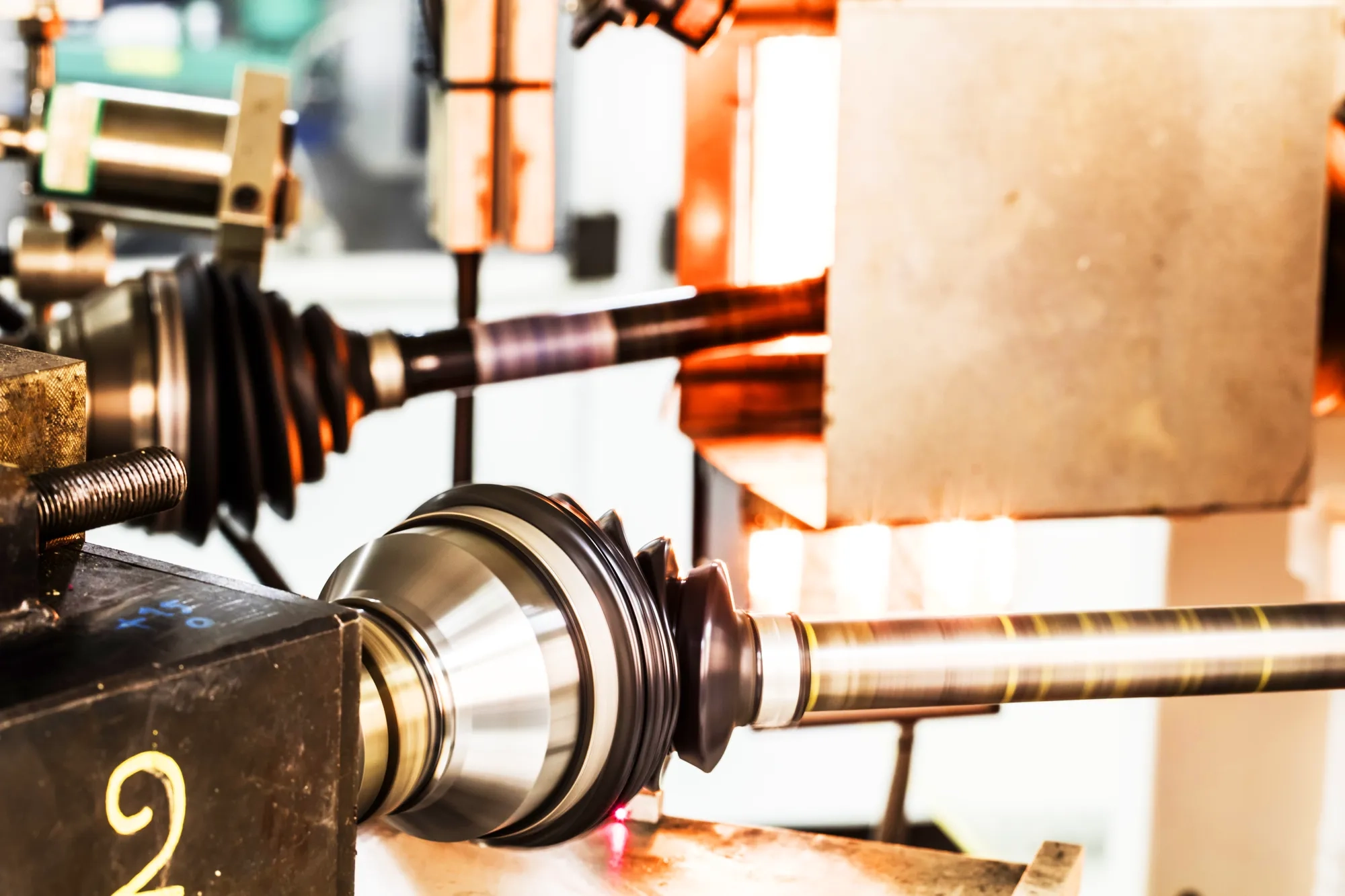 Constant Velocity Joint (CVJ) boot being tested on a high-temperature bench rig at an angle to evaluate its resistance to heat, rotation, and mechanical stress.