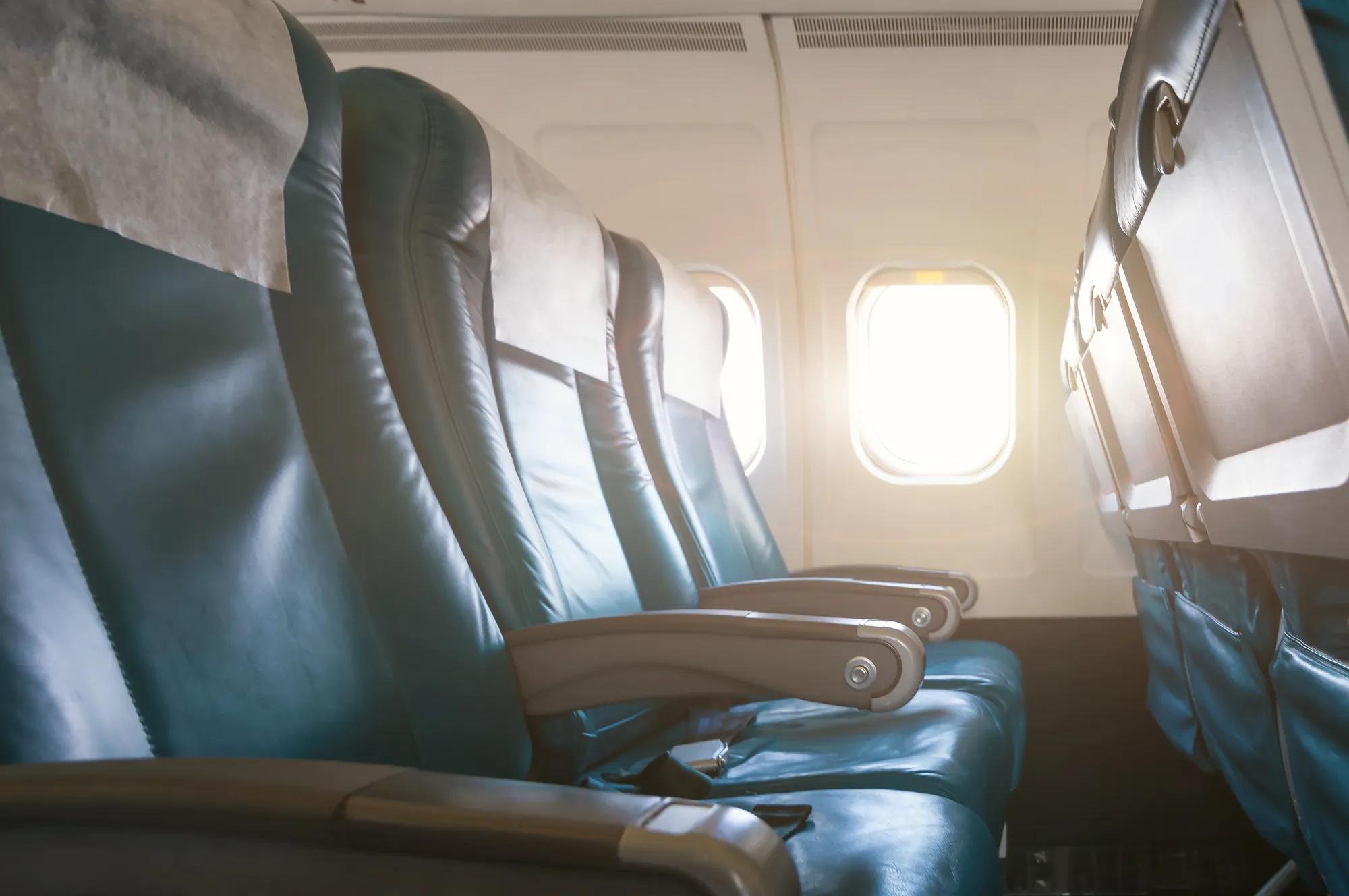 Empty aircraft seats and windows with sun light.