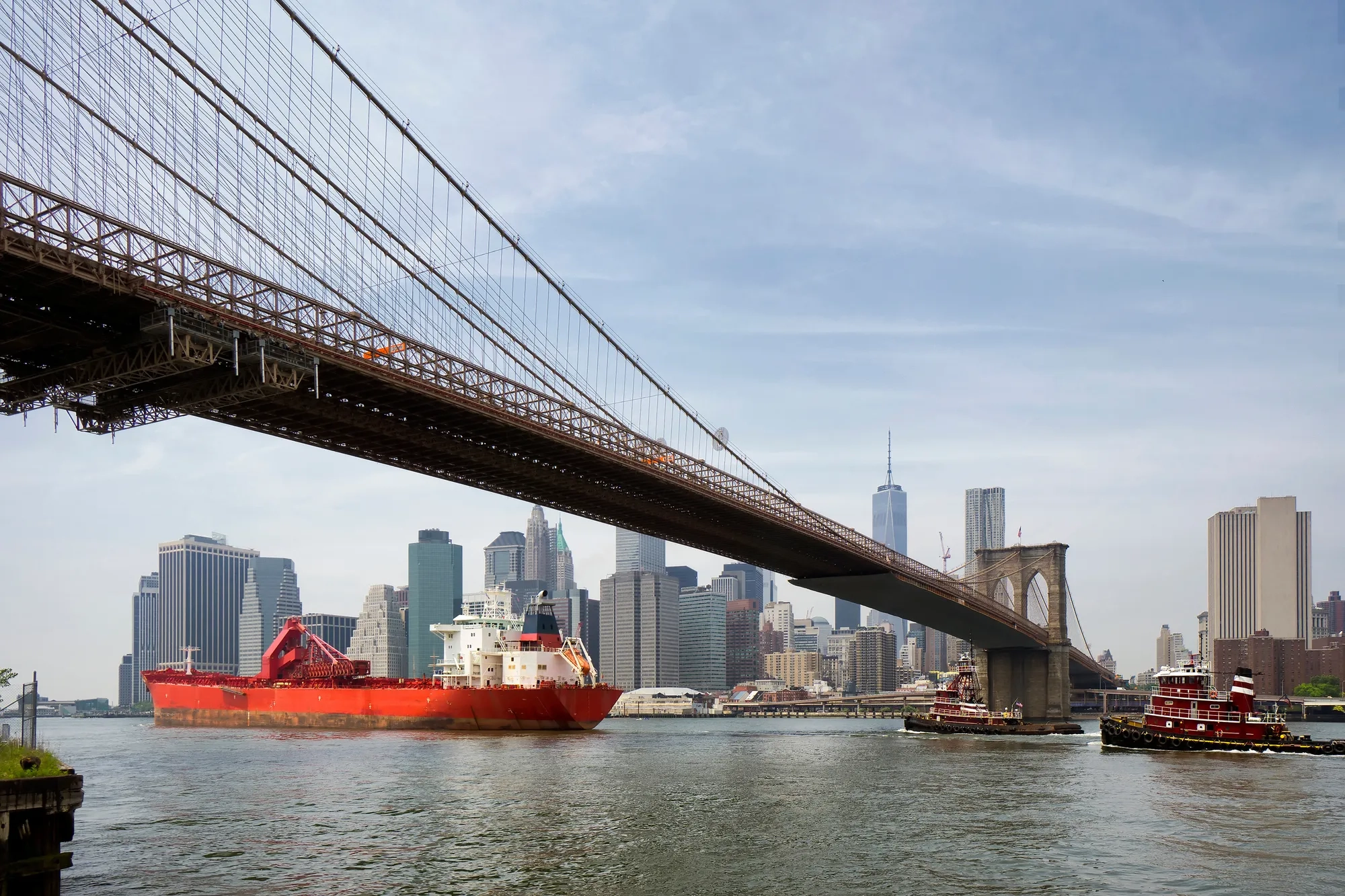 cargo ship and tug boat under brooklyn bridge, New York City