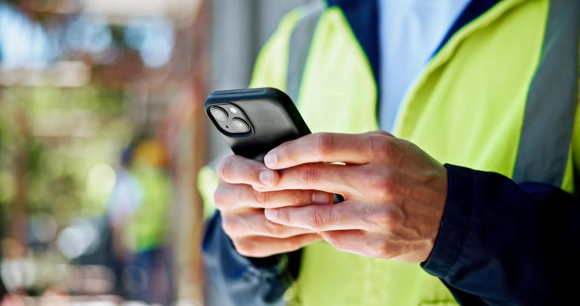 Hands, phone and construction site with texting, person or contact with info for building development. Engineer, smartphone and check with network, notification and mobile app at property in Spain.