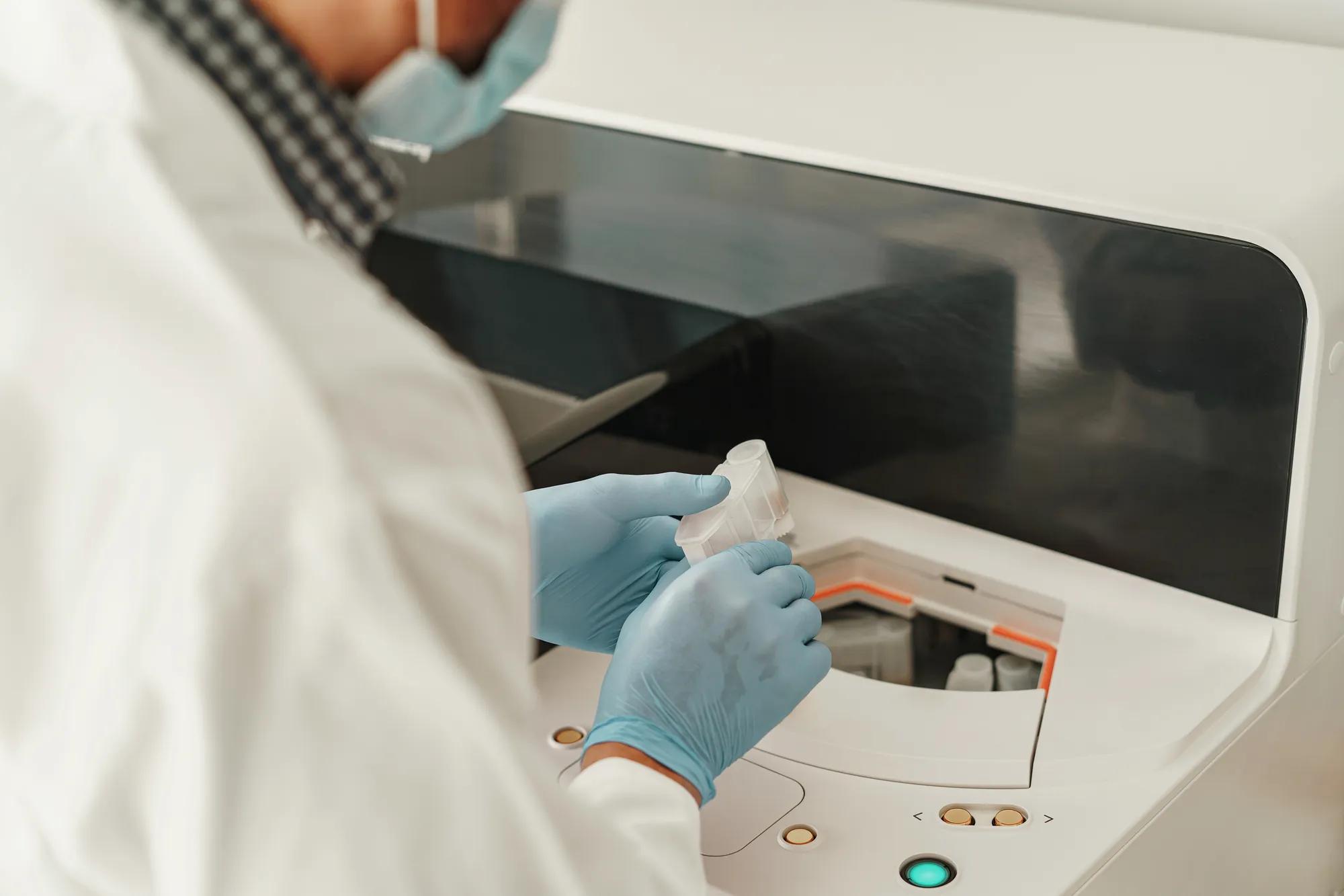 Close up of researcher hand in sterile glove putting plastic tube into laboratory centrifuge