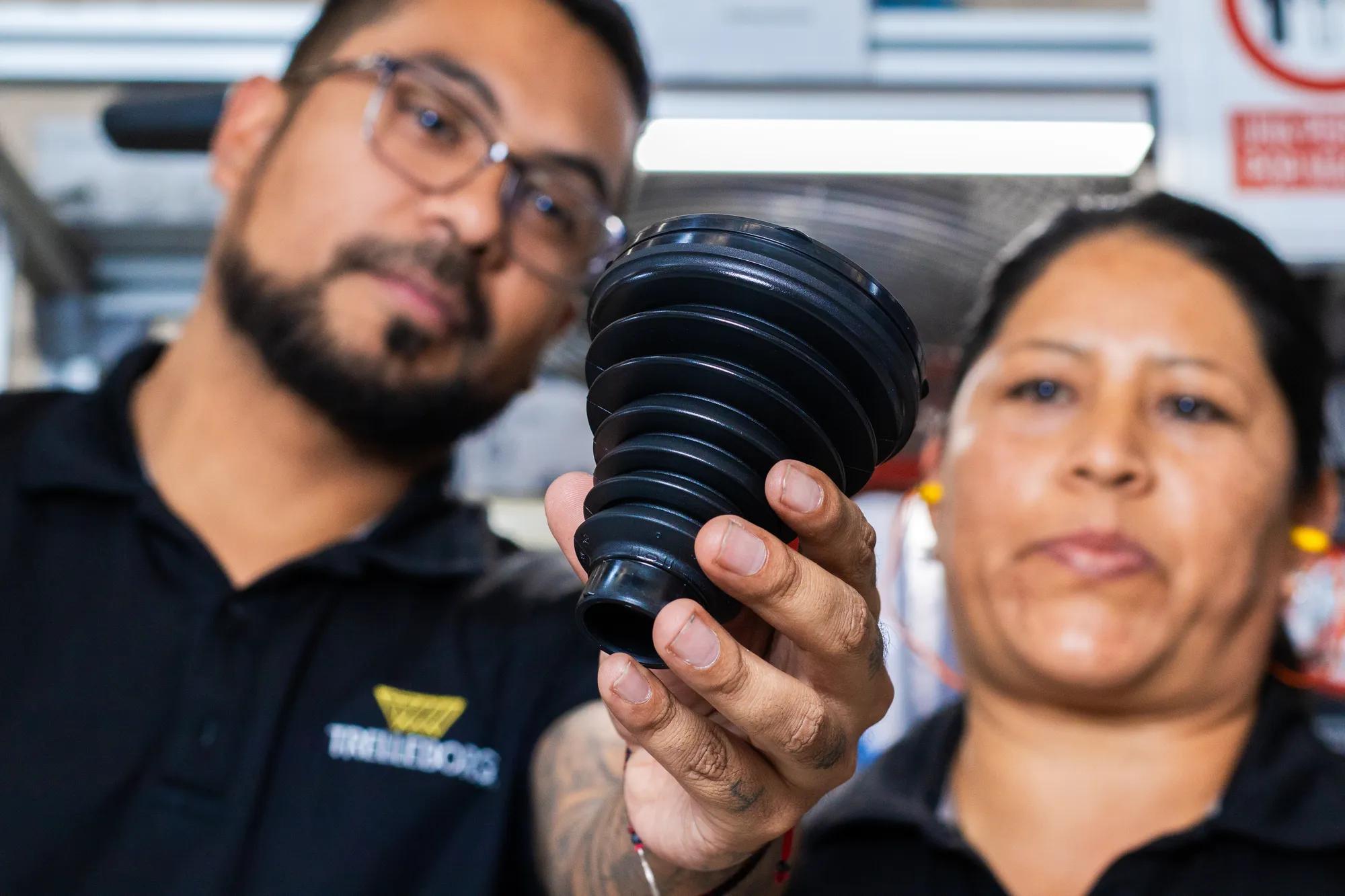 Two operators performing a four-eye quality control inspection on a CVJ boot.